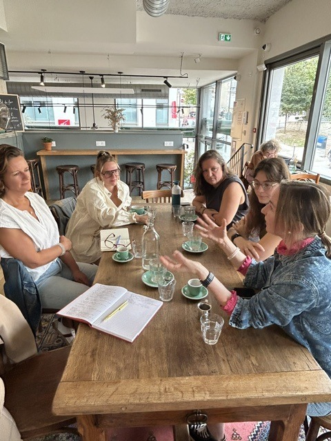 Participantes en pleine discussion autour d'un carnet ouvert lors d'un Café Bloomies