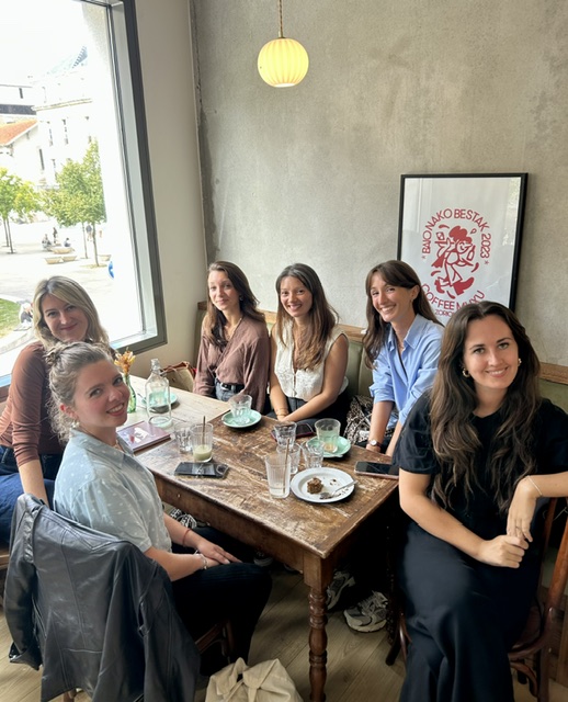 Entrepreneuses souriantes réunies devant une affiche rouge lors d'un Café Bloomies